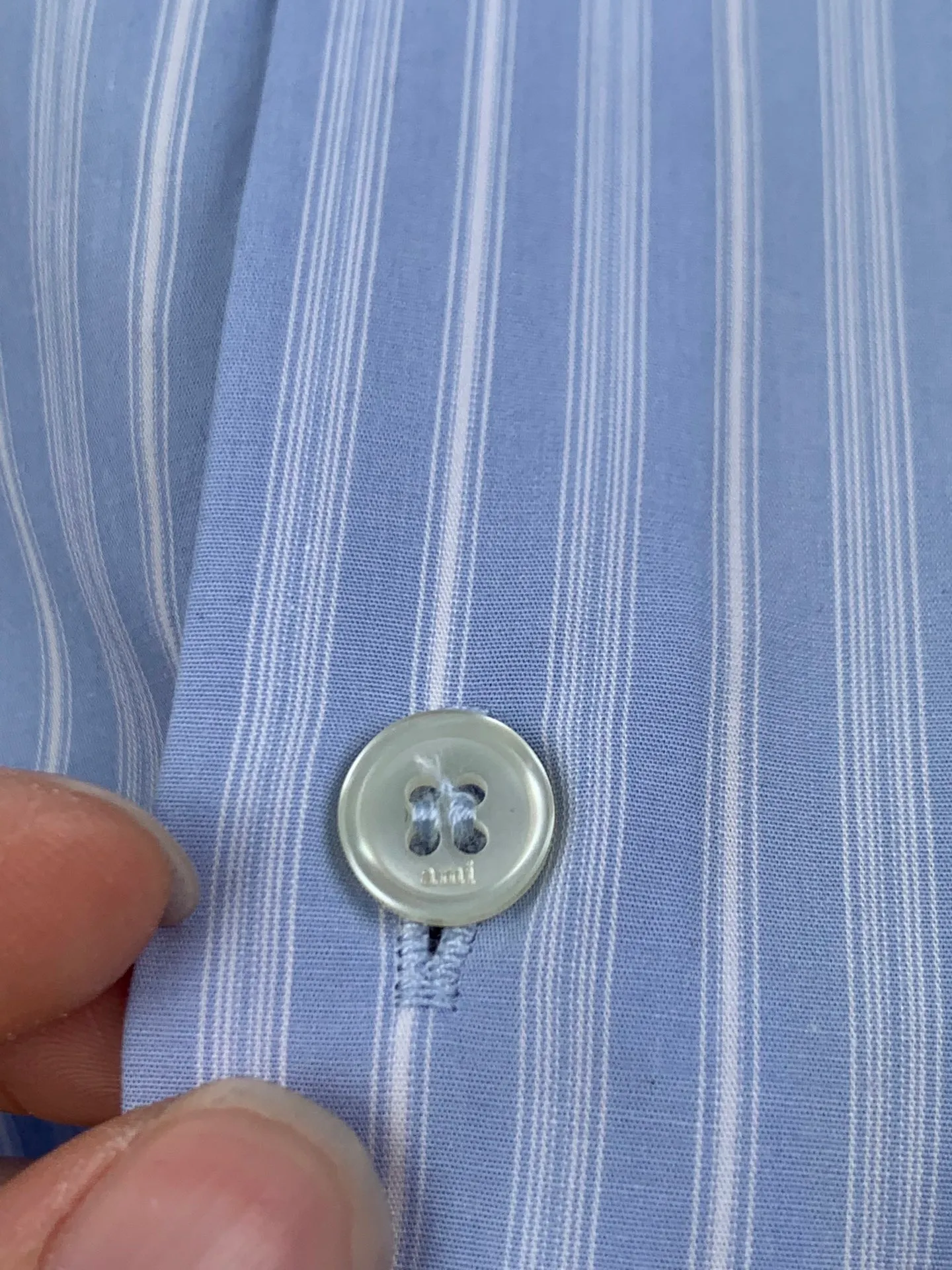 AMI embroidered love heart decorated blue and white striped long-sleeved shirt. Fabric selection: Made of 100% cotton poplin fabric. The pure cotton fiber can quickly absorb moisture and sweat, making it refreshing and not stuffy when worn for a long time. The unique plain weaving process of poplin makes the fabric both soft and skeletal, not easy to wrinkle and deform, and the upper body is neat and clean. Coupled with the fine blue and white stripes all over the body, the light color scheme is gentle and elegant, which can meet the needs of different scenes. Process 1: Accurately mark the embroidery position on the chest patch pocket to ensure that the pattern does not shift and does not destroy the overall beauty of the striped fabric. High-count embroidery threads of the same color as the fabric are selected, and flat stitch embroidery technology is used. The stitches are evenly tracked, the edges are clean and neat, and the love outline is simple and smooth. It retains recognition without irritating the skin. It is blended into the striped texture in a low-key manner to avoid an abrupt feeling, while ensuring that the embroidery threads are Wear-Resistant. 2: After the embroidery is completed, perform high-temperature ironing and thread trimming to ensure that the pattern is smooth and compliant, and it is not easy to lose thread or warp after being worn for a long time. Details: 1. The collar seat adopts double-layer reinforcement technology, which is not easy to collapse and deform after long-term wear. The collar corner has a soft arc, which can modify the neck line without being too sharp, making it neat and decent. 2. The inner side of the placket has hidden hemming treatment to avoid burrs on the fabric, while enhancing structural stability and preventing it from deforming after multiple washes. Accessories: One to one customized buttons Size: S M L XL